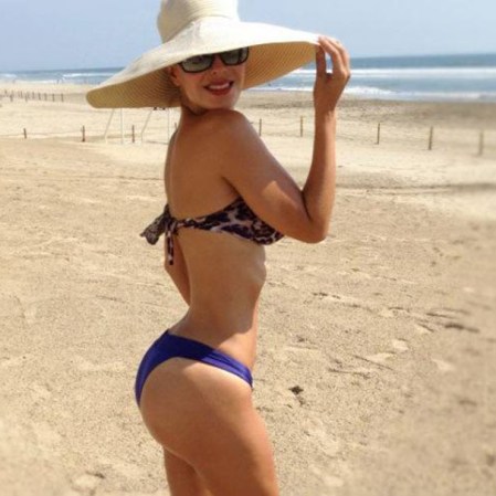 Muy hot con un sombrero de ala ancha en una desierta playa.
