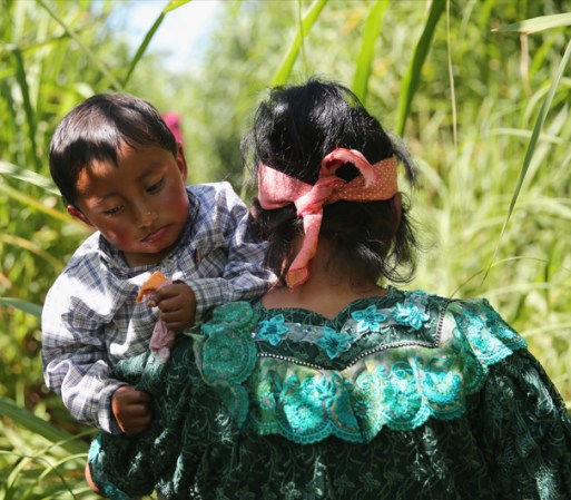 Una madre se encamina hacia el peligroso cruce, niño en brazos.