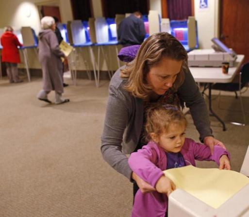 Una niña ayuda a su madre a emitir su voto en Janesville, Wisconsin.