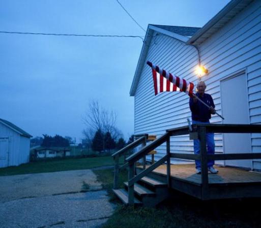 El inspector Jim Nodorft cuelga la bandera de Estados Unidos en la entrada de Smelser Town en Georgetown, Wisconsin, antes de que la gente comience a llegar.