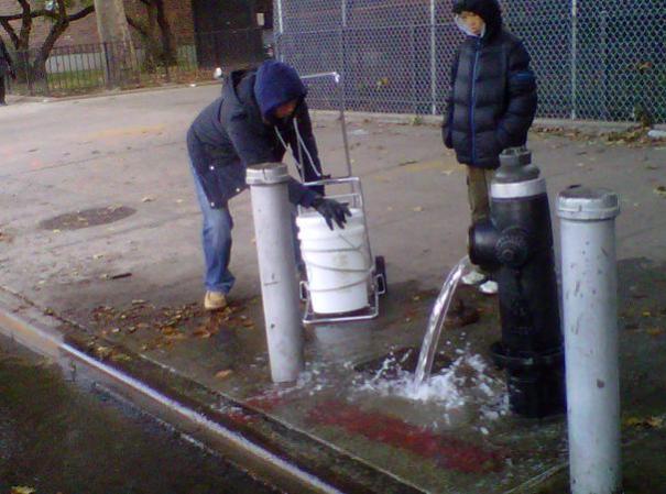 Personas se bañan con cántaros de agua.