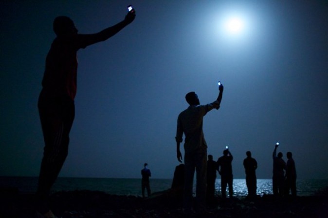 26 de febrero 2013. Inmigrantes en las afueras de Djibouti elevan sus celulares para intentar captar una señal de la vecina Somalia, con el fin de recibir mensajes de texto de sus familiares. Foto JOHN STANMEYER.