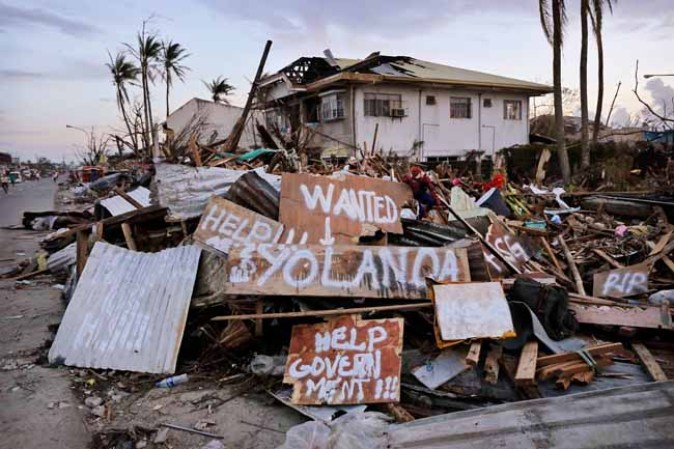 TACLOBAN, PHILIPPINES - NOVEMBER 13: Messages are painted on a demolished street in the aftermath of Typhoon Haiyan on November 13, 2013 in Tacloban, Leyte, Philippines. Typhoon Haiyan, packing maximum sustained winds of 195 mph (315 kph), slammed into the southern Philippines and left a trail of destruction in multiple provinces, forcing hundreds of thousands to evacuate and making travel by air and land to hard-hit provinces difficult. Around 10,000 people are feared dead in the strongest typhoon to hit the Philippines this year. (Photo by Kevin Frayer/Getty Images)