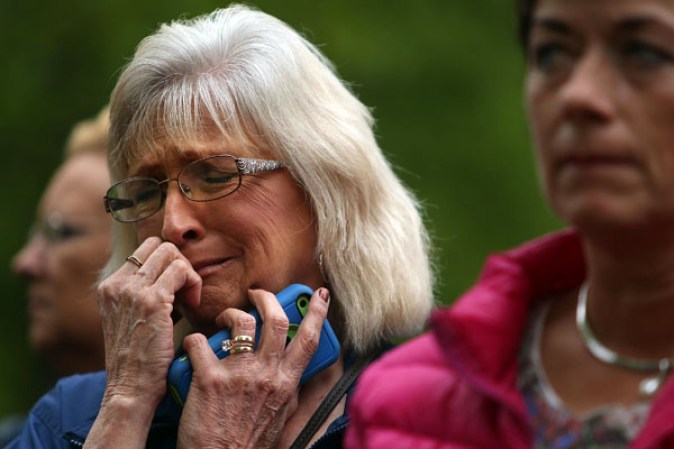 NEW YORK, NY - MAY 15: A woman pauses at the Ground Zero memorial site while watching the dedication ceremony of the National September 11 Memorial Museum in New York May 15, 2014 in New York City. The museum spans seven stories, mostly underground, and contains artifacts from the attack on the World Trade Center Towers on September 11, 2001 that include the 80 ft high tridents, the so-called "Ground Zero Cross," the destroyed remains of Company 21's New York Fire Department Engine as well as smaller items such as letter that fell from a hijacked plane and posters of missing loved ones projected onto the wall of the museum. The museum will open to the public on May 21. (Photo by Spencer Platt/Getty Images)