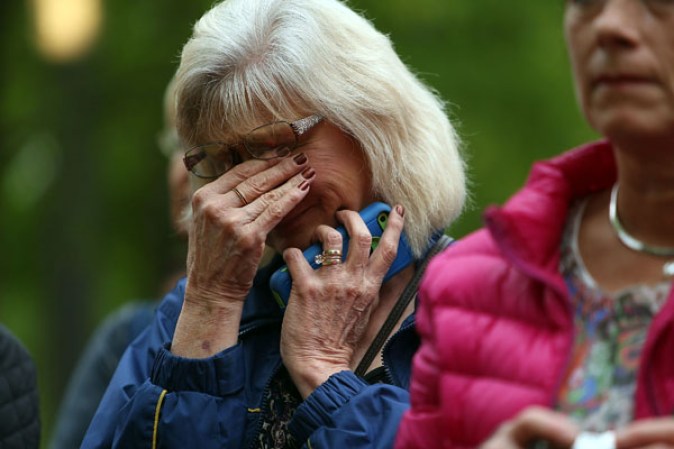NEW YORK, NY - MAY 15: A woman wipes away tears at the Ground Zero memorial site while watching the dedication ceremony of the National September 11 Memorial Museum at in New York May 15, 2014 in New York City. The museum spans seven stories, mostly underground, and contains artifacts from the attack on the World Trade Center Towers on September 11, 2001 that include the 80 ft high tridents, the so-called "Ground Zero Cross," the destroyed remains of Company 21's New York Fire Department Engine as well as smaller items such as letter that fell from a hijacked plane and posters of missing loved ones projected onto the wall of the museum. The museum will open to the public on May 21. (Photo by Spencer Platt/Getty Images)