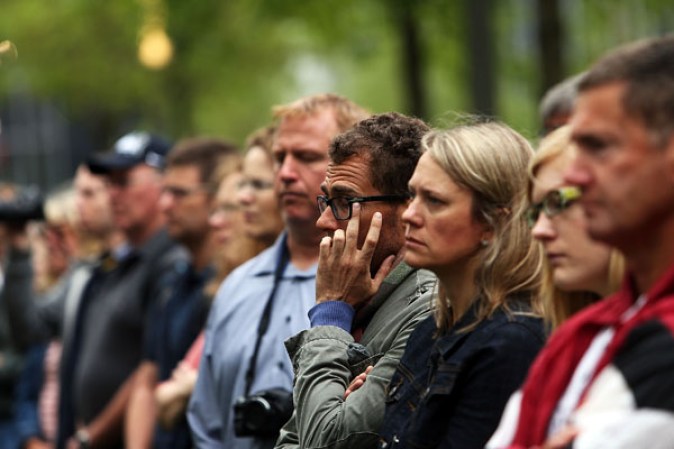NEW YORK, NY - MAY 15: People watch a live video from the Ground Zero memorial site of the dedication ceremony of the National September 11 Memorial Museum in New York May 15, 2014 in New York City. The museum spans seven stories, mostly underground, and contains artifacts from the attack on the World Trade Center Towers on September 11, 2001 that include the 80 ft high tridents, the so-called "Ground Zero Cross," the destroyed remains of Company 21's New York Fire Department Engine as well as smaller items such as letter that fell from a hijacked plane and posters of missing loved ones projected onto the wall of the museum. The museum will open to the public on May 21. (Photo by Spencer Platt/Getty Images)