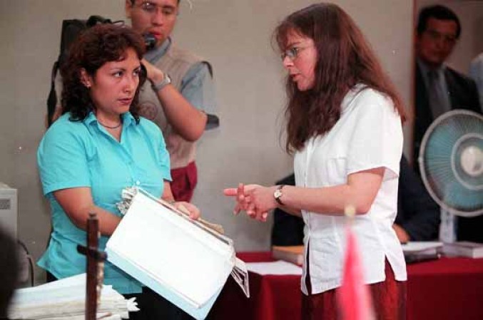 Un oficial de la corte en Perú muestra fotos a La Americana Lori Berenson condenada a prisión por traición en Abril 9, 2001.