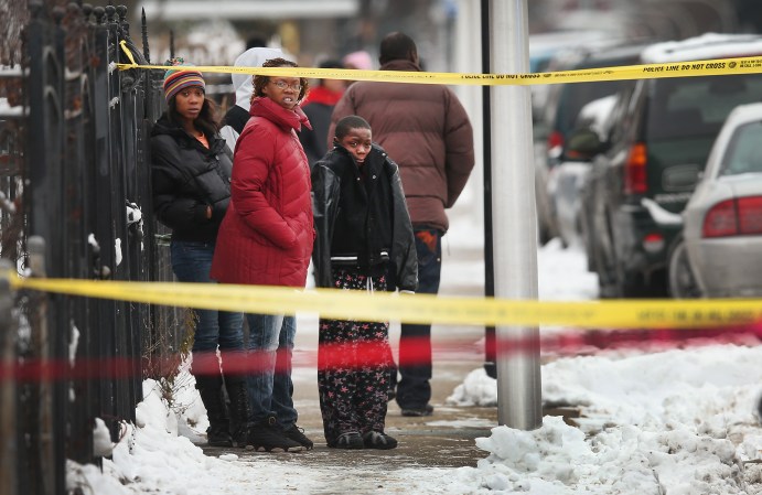 CHICAGO, IL - DECEMBER 14: Neighborhood residents watch as police investigate a homicide scene after a 24-year-old man was found dead with a gunshot to his back in the Lawndale neighborhood on December 15, 2013 in Chicago, Illinois. At around 7:30 a.m. someone reported finding the body lying on a sidewalk. Residents at the scene reported hearing gunshots around 3:00 a.m.. Chicago has had more than 400 homicides in 2013. Last year the city reported more than 500. ( Photo by Scott Olson/Getty Images ) )