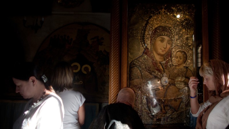 Varias mujeres se reúnen al interior de la iglesia cerca de una imagen de la Virgen María y el niño Jesús.