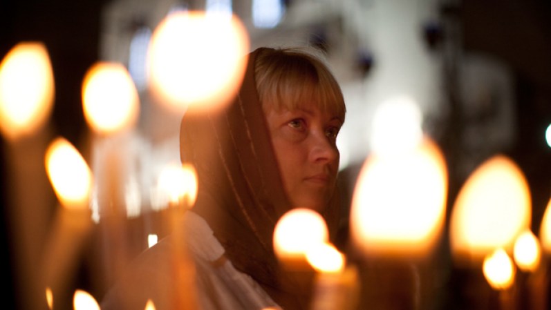 Una mujer reza rodeada de velas en el lugar sagrado.