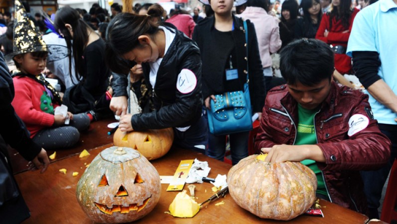 Un grupo de personas tallan calabazas de Halloween en una calle peatonal en Wuhan, China