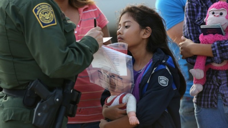 Esta niña inmigrante salvadoreña Stefany Marjorie, de 8 años, mira como la Patrulla Fronteriza registra su información familiar el 24 de julio de 2014 en Mission, Texas. Como la mayoría del reciente aumento de mujeres y niños inmigrantes centroamericanos, su familia llevó documentos, a menudo certificados de nacimiento, para acreditar su nacionalidad a los funcionarios de EEUU en la frontera. Decenas de miles de familias de inmigrantes y menores no acompañados procedentes de América Central han cruzado ilegalmente a los Estados Unidos este año, y se presentaron a los agentes federales, causando una crisis humanitaria en la frontera entre Estados Unidos y México. El Valle del Río Grande en Texas se ha convertido en el epicentro de la crisis más reciente de inmigrantes, ya que muchos de ellos entran ilegalmente de México por ese sector, más que por cualquier otra parte de las 1,933 millas de frontera con México.
