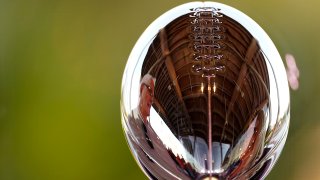 A man is reflected in the Lombardi Trophy