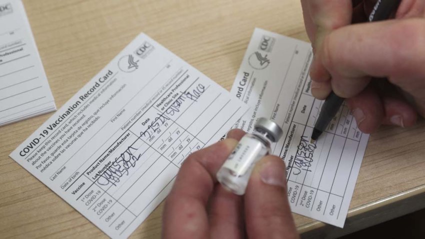 A healthcare worker fills out a Covid-19 Vaccination Record Card.