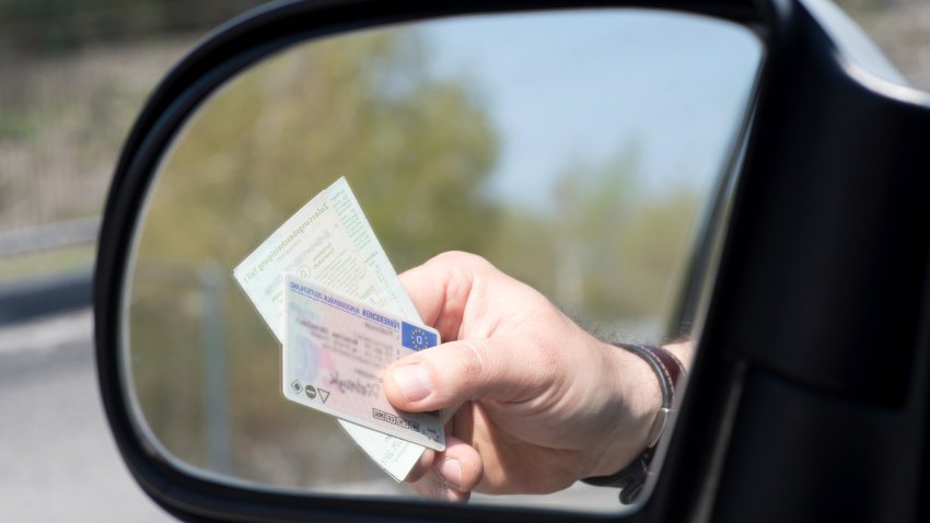 Ein Mann zeigt Führerschein und Fahrzeugschein bei einer Kontrolle