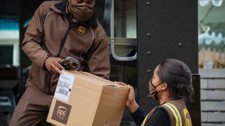 Conductor de UPS dando paquete a ayudante de UPS