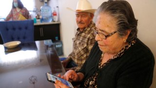 Dos personas adultas mayores miran la pantalla de un celular que sostiene una de ellas