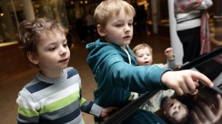 Tres ninos tocando una exhibicion interactiva de un museo.