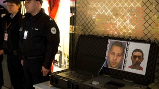 Oficiales de policía junto al aviso de búsqueda del terrorista Salah Abdeslam (L) y Mohamed Abrini el 3 de diciembre de 2015 en el aeropuerto Roissy-Charles-de-Gaulle en Roissy-en-France, en las afueras de París.