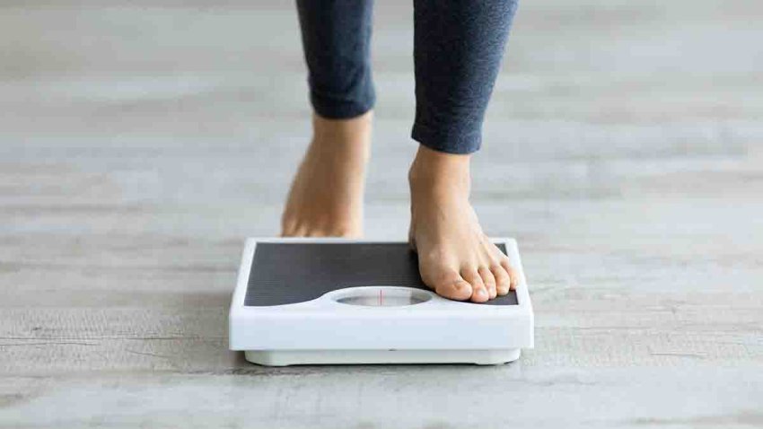 Unrecognizable young Indian woman stepping on scales to measure her weight at home, closeup of feet. Cropped view of millennial lady checking result of her slimming diet. Healthy living concept