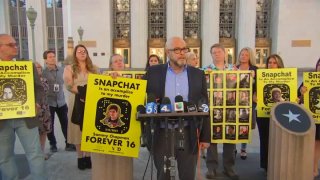 Parents hold placards with the picture of their deceased children superimposed on a Snapchat background.