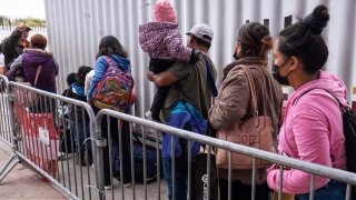 Una familia llega a un punto de ingreso en EEUU en la frontera con México, en California, para pedir asilo.