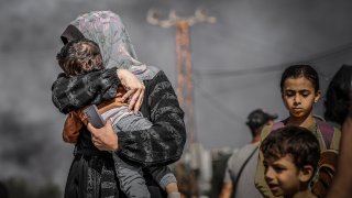 Una madre protege a uno de sus pequeños durante un reciente ataque israelí en Gaza.