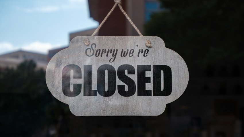 Close-up of “Sorry, We’re Closed” sign hanging from store’s glass door