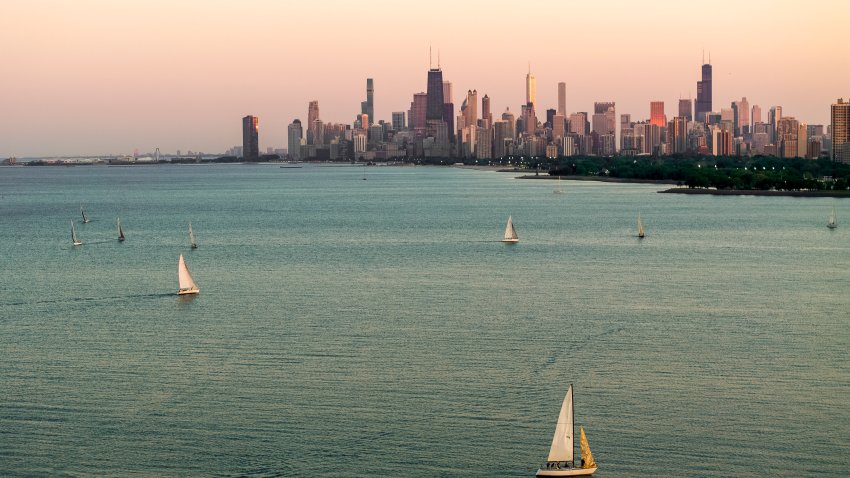 A captivating photograph capturing sailboats gracefully gliding on Lake Michigan with the iconic Chicago skyline in the background during a beautiful sunset. The soft hues of the evening sky cast a warm glow over the cityscape and the calm waters, creating a serene and picturesque scene