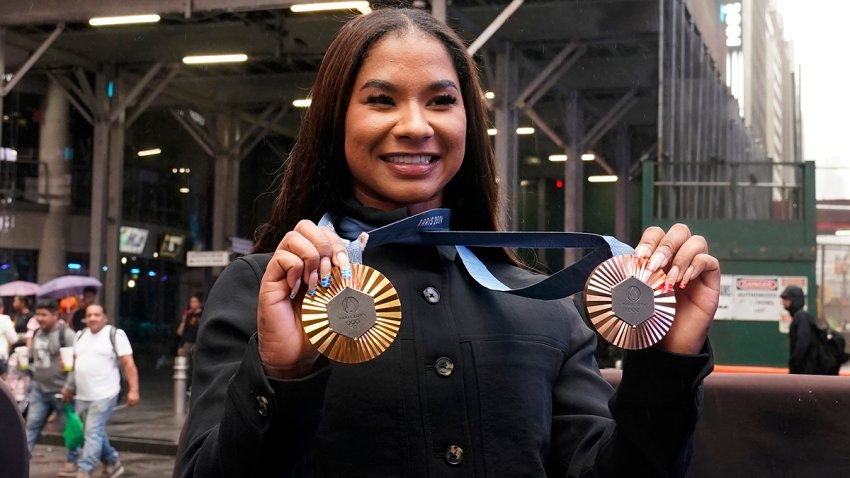 La gimnasta estadounidense y medallista olímpica Jordan Chiles muestra sus medallas tras el cierre del Nasdaq MarketSite, en Times Square, Nueva York, el jueves 8 de agosto de 2024. (AP Foto/Richard Drew)