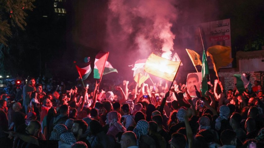 Protesters lift Palestinian flags and a portrait of Mohammed Deif chief of Al-Qassam Brigades, Hamas’ military wing, during rally at the entrance of the French embassy complex in Beirut early on October 18, 2023, in support of Palestinians after a strike on the Ahli Arab hospital in central Gaza that killed hundreds. Israel and Palestinians traded blame for the incident, which an “outraged and deeply saddened” US President Joe Biden denounced while en route to the Middle East. (Photo by ANWAR AMRO / AFP) (Photo by ANWAR AMRO/AFP via Getty Images)