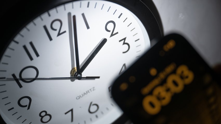 21 March 2023, Hesse, Gießen: A smartphone displays the time “03:03”, while on an analog clock it is still 02:03. On March 26, the clocks will be set forward at 02:00 to 03:00 and daylight saving time will begin. Photo: Sebastian Christoph Gollnow/dpa (Photo by Sebastian Gollnow/picture alliance via Getty Images)