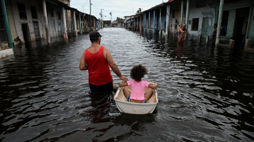 People walk through a flooded street in Batabano, Mayabeque province, Cuba on September 26, 2024, after the passage of Hurricane Helene.