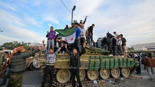 La gente celebra con combatientes antigubernamentales en la Plaza Omeya en Damasco el 8 de diciembre de 2024. Los rebeldes liderados por islamistas declararon que habían tomado Damasco en una ofensiva relámpago el 8 de diciembre, lo que hizo huir al presidente Bashar al-Assad y puso fin a cinco décadas de gobierno del Baaz en Siria.