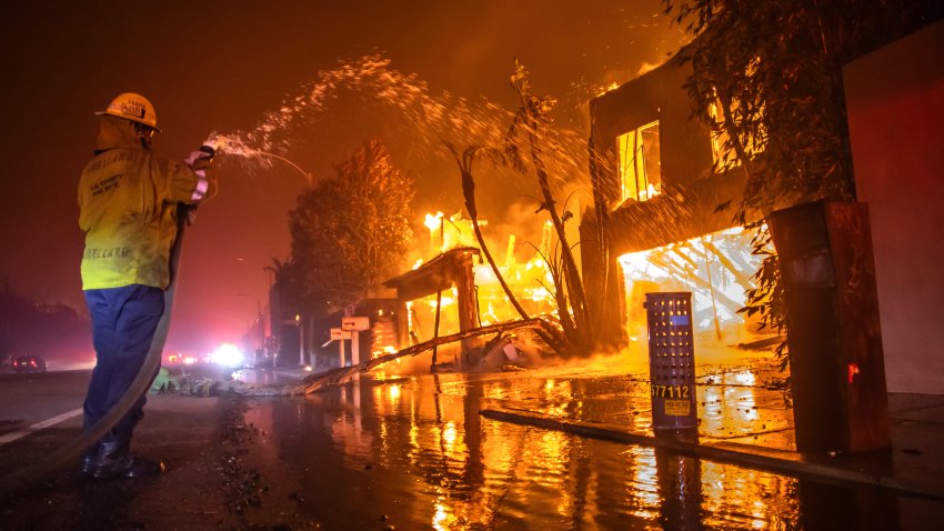 LOS ANGELES, CALIFORNIA – JANUARY 8: A firefighter battles the Palisades Fire while it burns homes at Pacific Coast Highway amid a powerful windstorm on January 8, 2025 in Los Angeles, California.  The fast-moving wildfire has grown to more than 2900-acres and is threatening homes in the coastal neighborhood amid intense Santa Ana Winds and dry conditions in Southern California. (Photo by Apu Gomes/Getty Images)