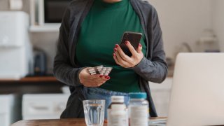 Paciente asiática que busca detalles de enfermedades y medicamentos mediante un teléfono inteligente con IA.