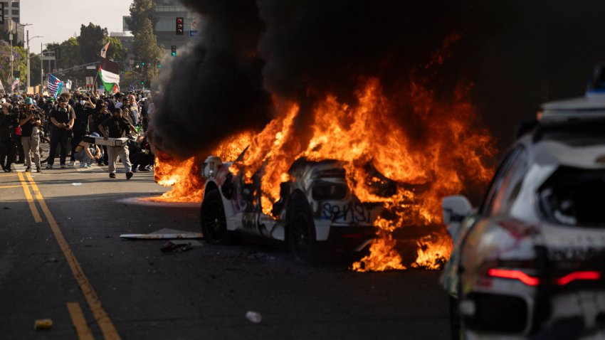 Waymo cars are set on fire as protesters clash with law enforcement near the federal building during a protest in response to federal immigration operations in Los Angeles, California, on June 8, 2025. US President Donald Trump deployed 2,000 troops on June 7 to handle escalating protests against immigration enforcement raids in the Los Angeles area, a move the state’s governor termed “purposefully inflammatory.” Federal agents clashed with angry crowds in a Los Angeles suburb as protests stretched into a second night Saturday, shooting flash-bang grenades and shutting part of a freeway amid raids on undocumented migrants, reports said. (Photo by ETIENNE LAURENT / AFP) (Photo by ETIENNE LAURENT/AFP via Getty Images)