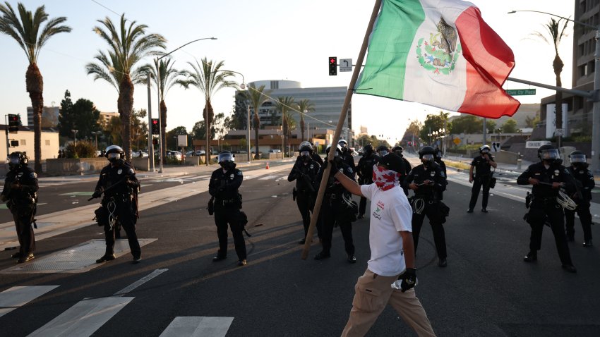 A person holds a Mexican flag outside the United States Citizenship and Immigration Services (USCIS) Santa Ana Field Office after reports of Immigration and Customs Enforcement (ICE) raids in Santa Ana, California, on June 9, 2025. The City of Santa Ana released a statement on Facebook acknowledging the ICE activity and the “fear and uncertainty” it would cause for some community . President Donald Trump’s istration said on June 9 that it was sending 700 US Marines and thousands more National Guard troops to Los Angeles, sparking a furious response from California’s governor over the “deranged” deployment. (Photo by Patrick T. Fallon / AFP) (Photo by PATRICK T. FALLON/AFP via Getty Images)