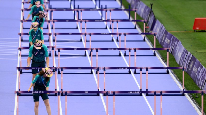 Volunteers prepare hurdles before the women's 100m hurdles during the Paris 2024 Olympic Games.