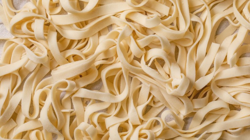 Fresh italian homemade raw uncooked pasta tagliatelle with semolina flour on cotton cloth. Close up. Food background
